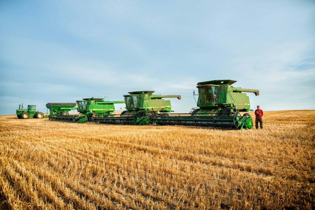 Produtor rural ao lado de colheitadeiras na lavoura colhida